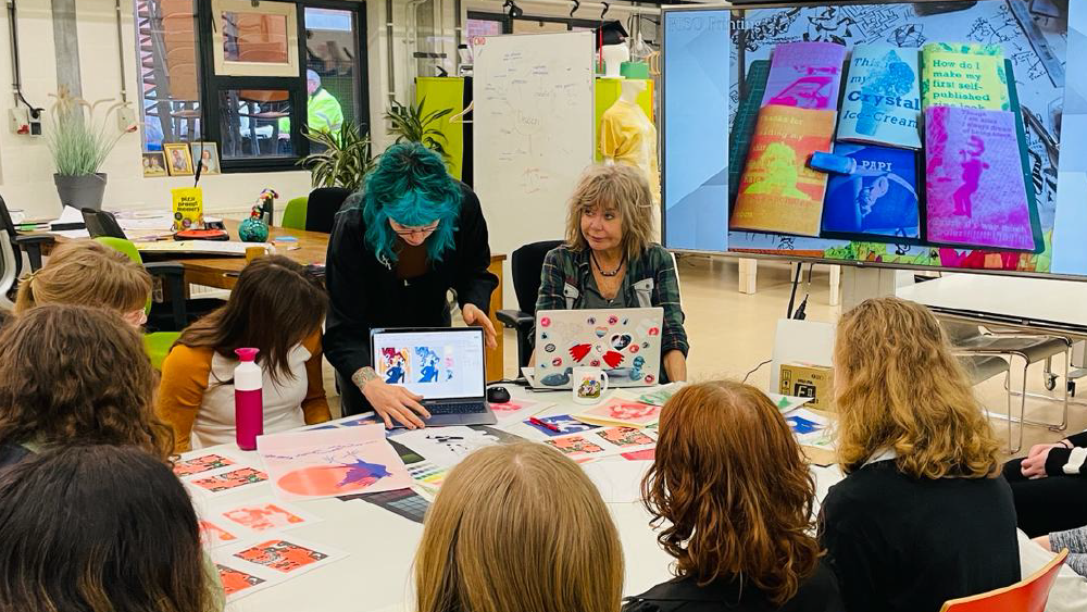 Pleun, met een kleurrijke foto van haarzelf, collega en studenten tijdens een workshop RISO aan studenten in het CMD TECHLAB